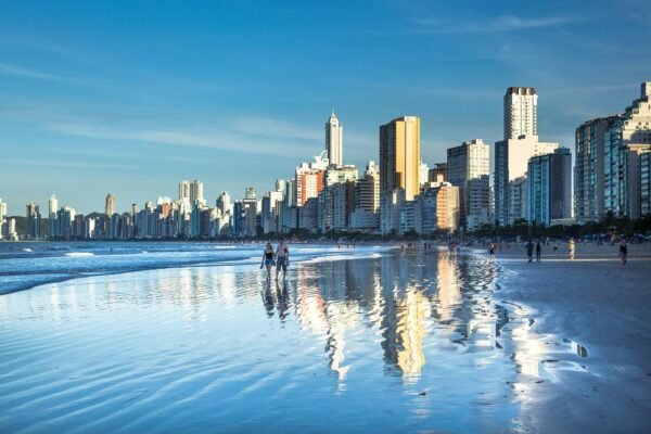 Stunning view of Balneário Camboriú's modern skyline reflecting on the beach at daytime.