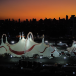 Vista externa da grandiosa tenda do Mirage Circus iluminada ao lado do ExpoCentro em Balneário Camboriú sob o céu noturno.