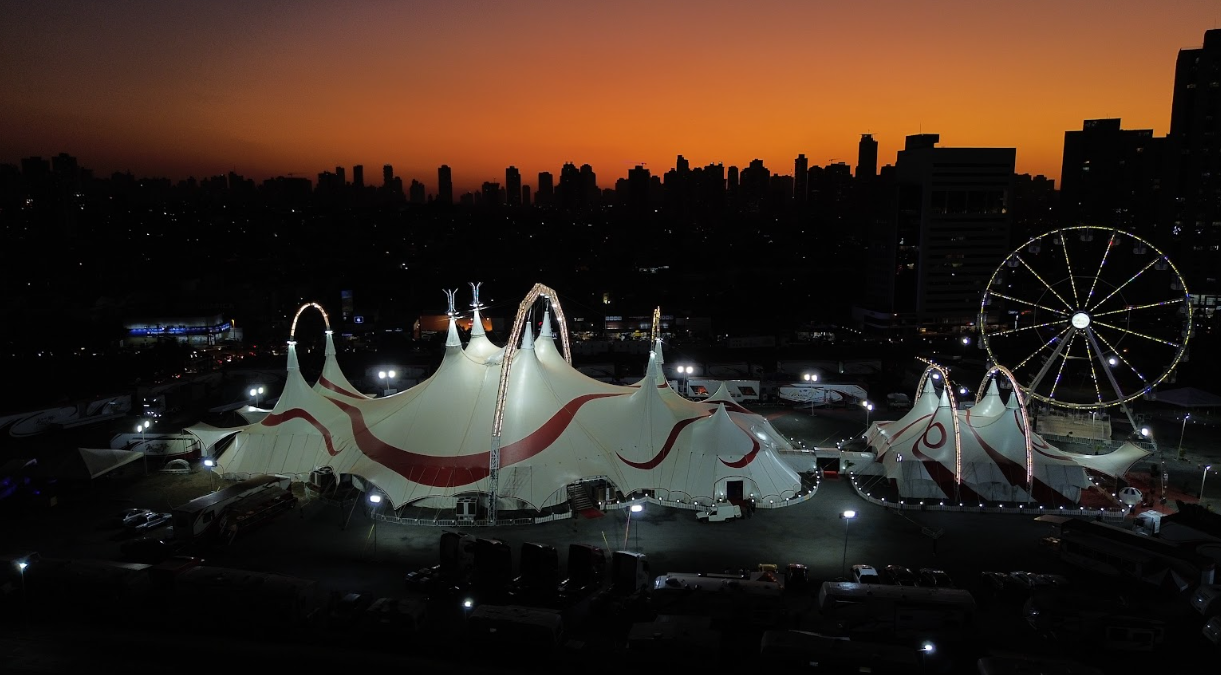 Vista externa da grandiosa tenda do Mirage Circus iluminada ao lado do ExpoCentro em Balneário Camboriú sob o céu noturno.