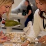 uas empresárias membras VIP do movimento Elas Conectam analisando de perto detalhes de joias e brincos expostos em display de mesa corporativo durante evento em hotel de Itapema SC.