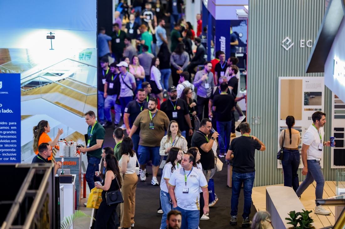 Visão aérea do corredor principal da Feira Construir Aí no Expocentro Balneário Camboriú, mostrando grande movimentação de profissionais, engenheiros, arquitetos e stands modernos do setor da construção civil.