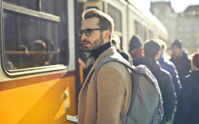 A stylish man with a backpack boards a tram in bustling Budapest, Hungary, during the day.